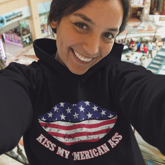 Woman wearing black Kiss My ’Merican Ass hoodie with stars-and-stripes lips graphic. Infidel Collective