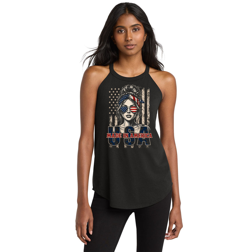 A woman modeling a black halter-neck tank top with a patriotic graphic on the front. The graphic features a stylized portrait of a woman wearing an American flag headscarf, a distressed American flag background, and the text 'MAKE AMERICA USA' in red, white, and blue.