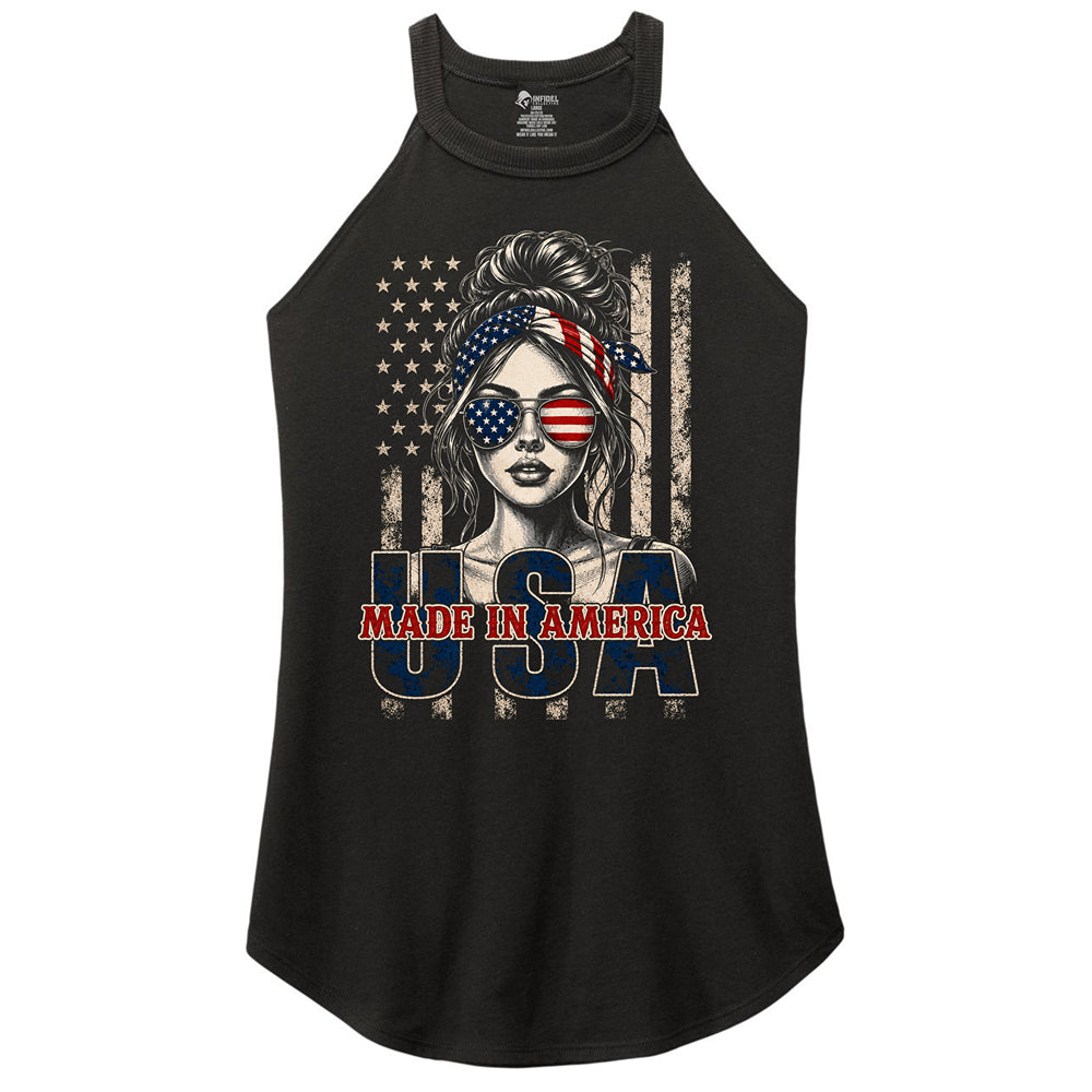 A black sleeveless racerback tank top featuring a patriotic graphic of a woman with an American flag bandana and sunglasses, set against a distressed American flag background with the text 'USA MADE IN AMERICA' printed below.