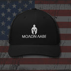 Black cap with white logo and text on an American flag background