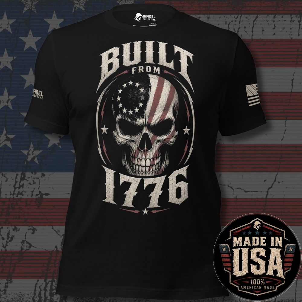 A black short-sleeve graphic T-shirt displayed against a distressed American flag background. The shirt features a large front graphic of a skull with an American flag pattern inside an oval, with the words 'BUILT FROM 1776' in distressed white lettering.