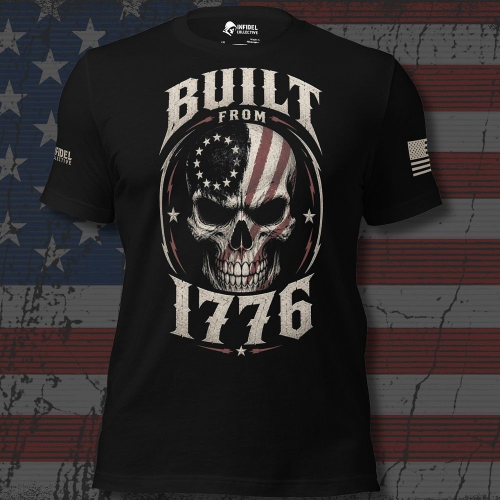 A black short-sleeve graphic T-shirt displayed against a distressed American flag background. The shirt features a large front graphic of a skull with an American flag pattern inside a circular emblem, with the words 'BUILT FROM 1776' in distressed white lettering.