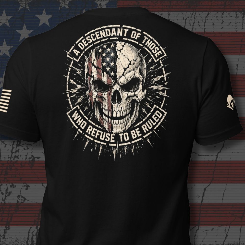 Infidel Collective black tee with cracked American flag skull and “A DESCENDANT OF THOSE WHO REFUSE TO BE RULED” back print