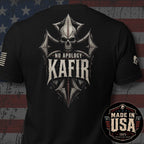 Black short-sleeve t-shirt shown from the back with a large distressed graphic featuring a skull, crossed elements, and the text 'NO APOLOGY KAFIR'. A circular 'MADE IN USA 100% AMERICAN MADE' badge appears in the lower right corner, and the shirt is photographed against a rustic American flag background.
