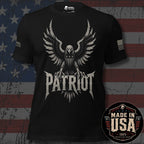 A black short-sleeve graphic T-shirt featuring a large distressed eagle with spread wings and the word "PATRIOT" in bold lettering below. USA American flag on the left sleeve and brand logo 'INFIDEL COLLECTIVE' on the right sleeve. The shirt is shown against a rustic American flag background. 100% Made in the USA.