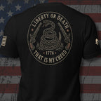 Infidel Collective black tee with coiled rattlesnake, flintlock pistols, “LIBERTY OR DEATH,” “1776,” and “THAT IS MY CREED” back print