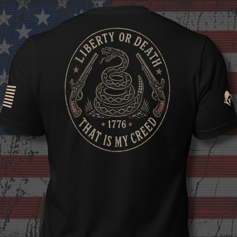 Infidel Collective black tee with coiled rattlesnake, flintlock pistols, “LIBERTY OR DEATH,” “1776,” and “THAT IS MY CREED” back print