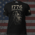 A black short-sleeve graphic T-shirt with distressed white text reading '1776 AMERICAN INFIDEL' and a large hooded figure graphic on the front. The shirt has a small logo on the neck and a small flag graphic on the sleeve, shown against a dark American flag background.