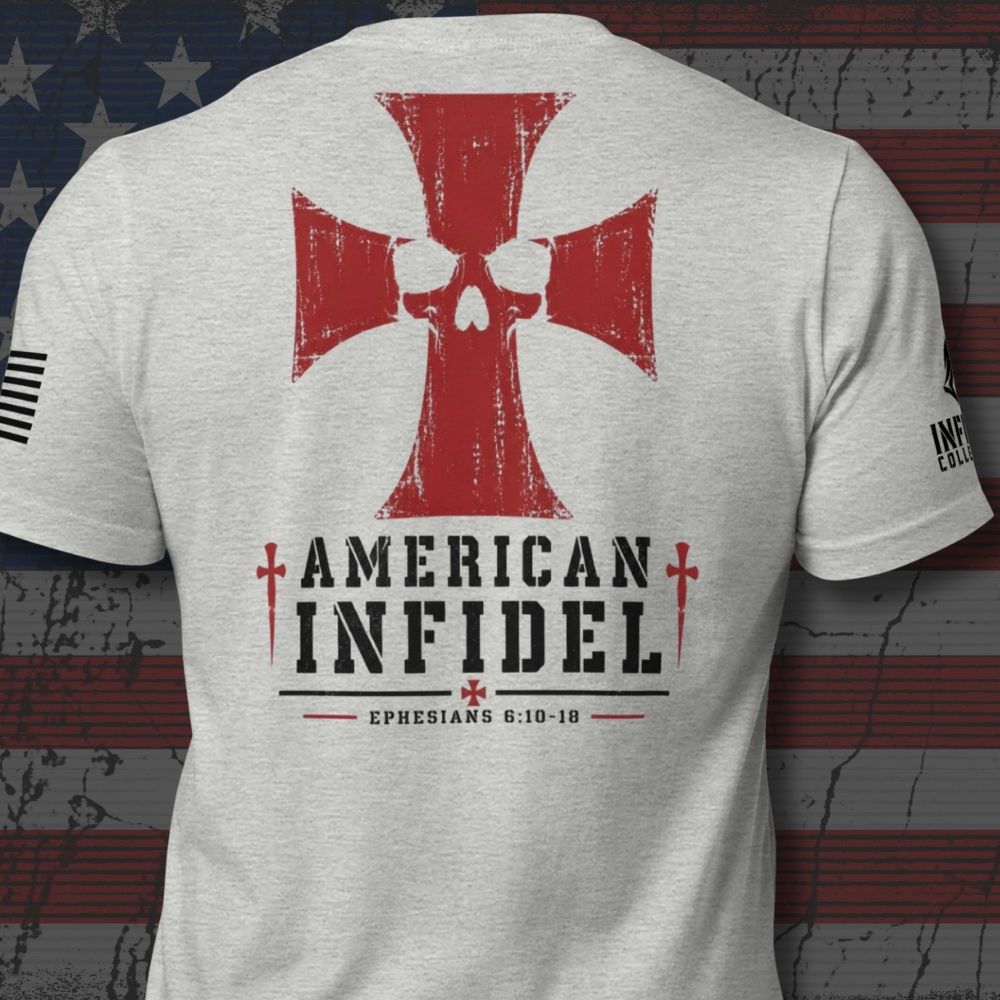 A light heather gray t-shirt shown from the back, featuring a large red Iron Cross with a skull design, the words 'AMERICAN INFIDEL' in black, and 'EPHESIANS 6:10-18' printed below. The shirt is displayed against a distressed American flag background.