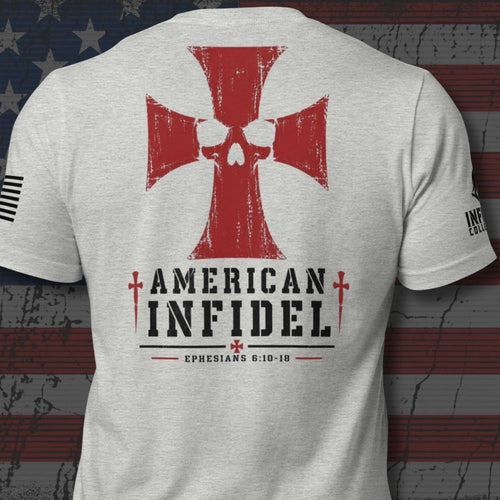 A light heather gray t-shirt shown from the back, featuring a large red Iron Cross with a skull design, the words 'AMERICAN INFIDEL' in black, and 'EPHESIANS 6:10-18' printed below. The shirt is displayed against a distressed American flag background.