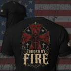 Black tee with back print featuring a hooded reaper, distressed red cross graphics, Christian cross symbols, and the text Forged By Fire