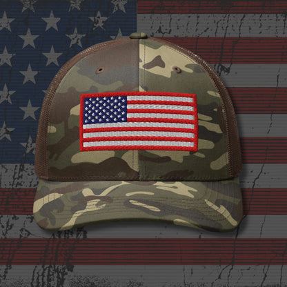 Camouflage cap with American flag patch on a background resembling the American flag.