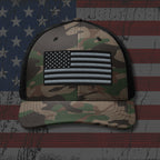 Camouflage cap with American flag patch on an American flag background