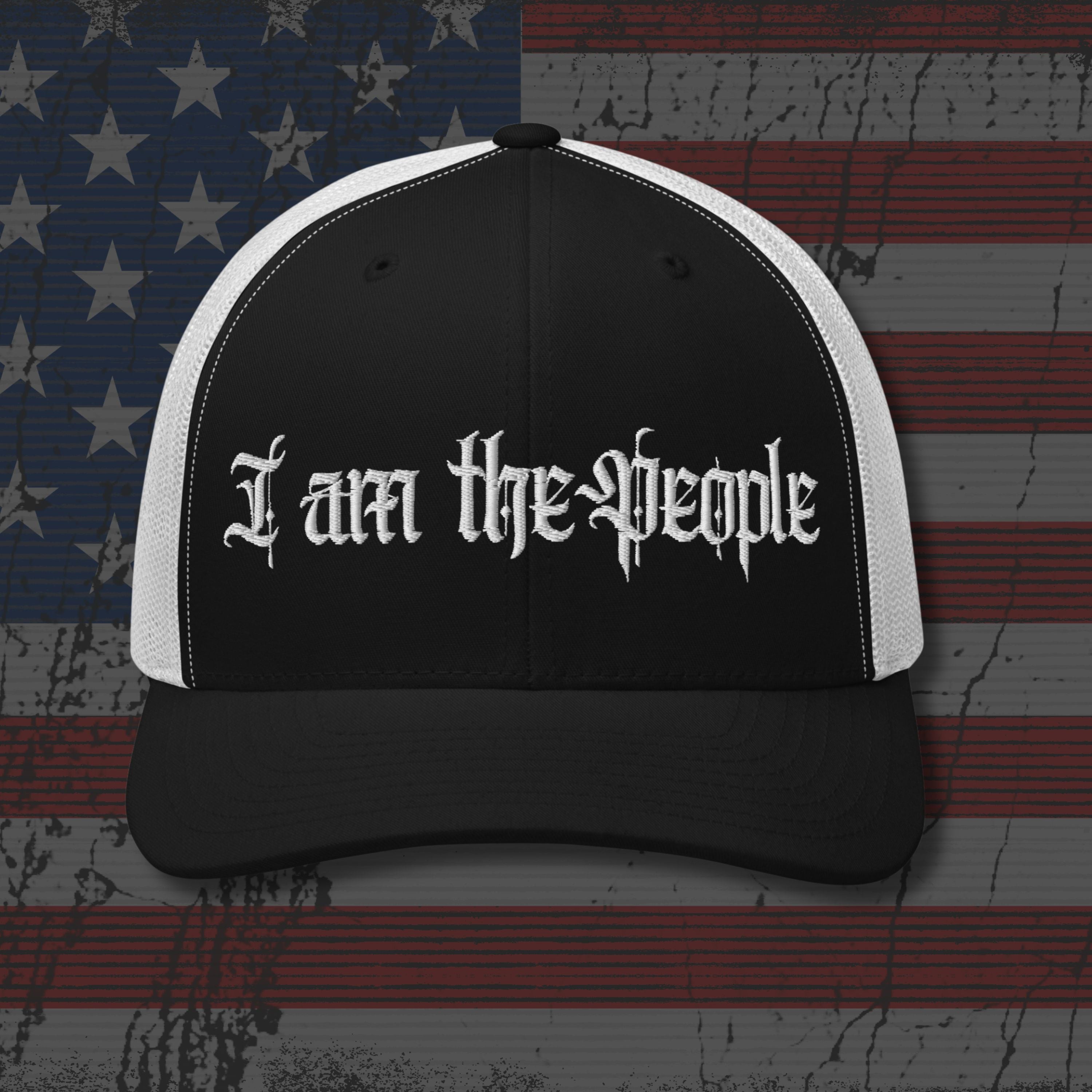 Black and white cap with 'I am the people' text on an American flag background