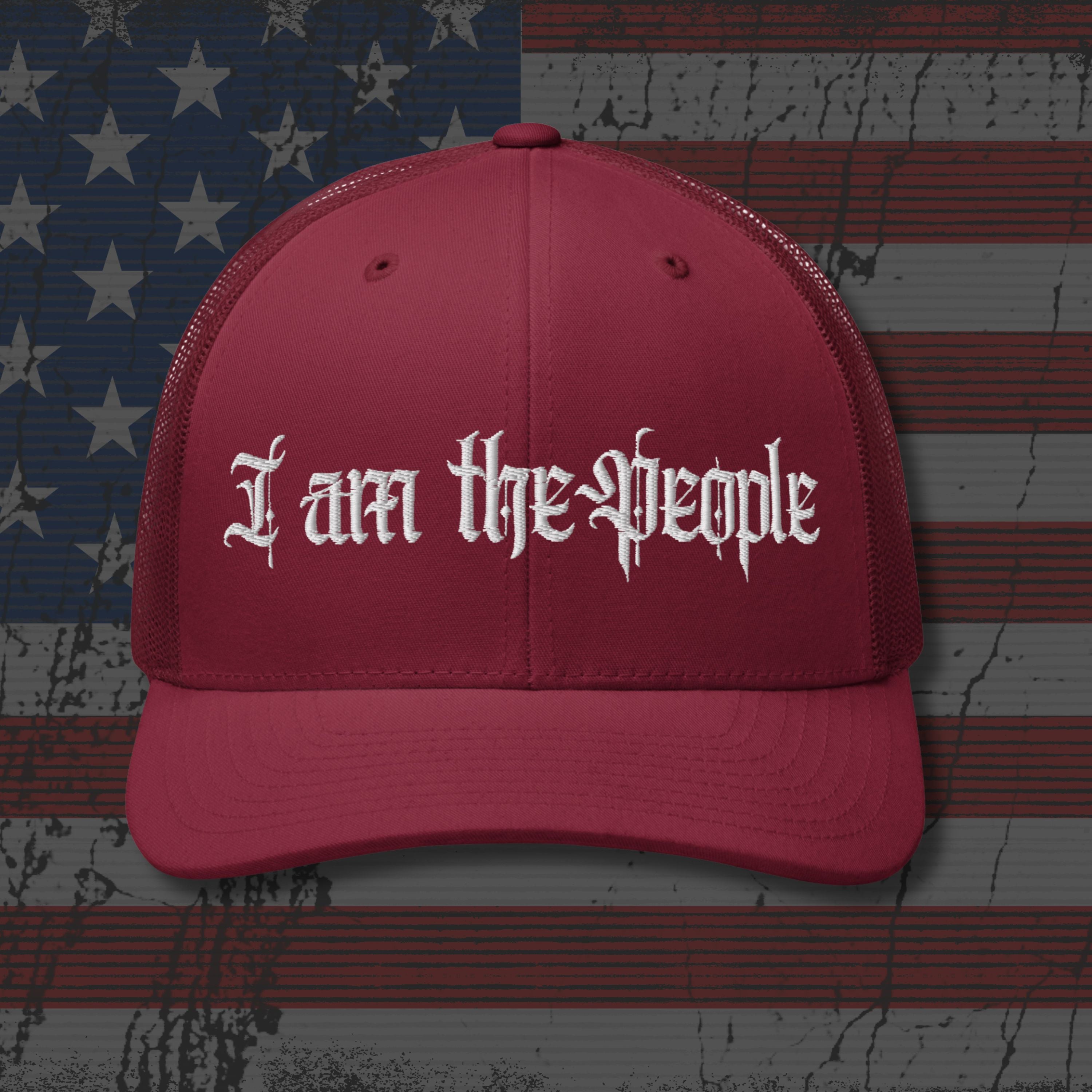 Red cap with 'I am the People' text on an American flag background