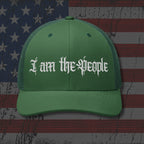 Green cap with 'I am the People' text on an American flag background