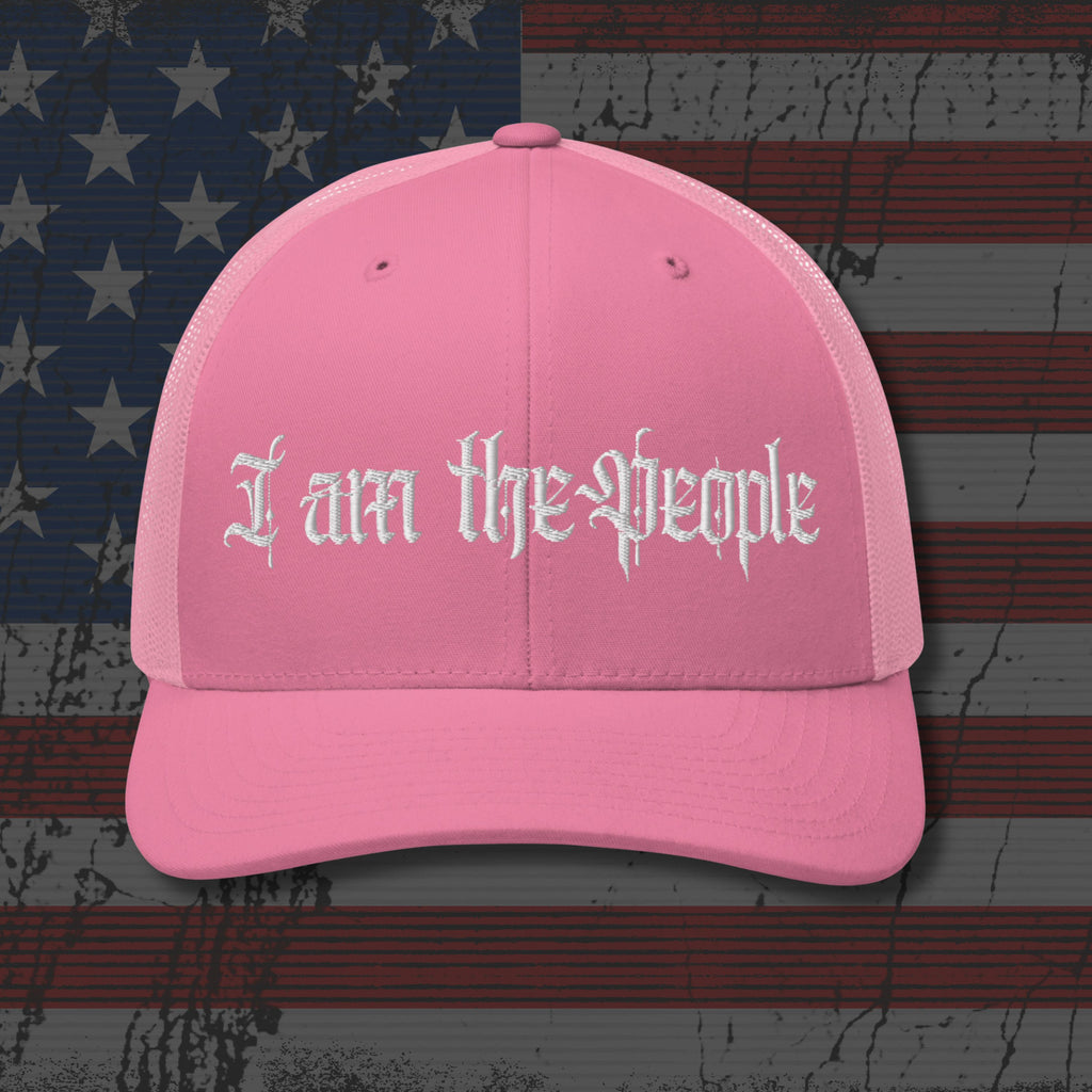 Pink cap with 'I am the people' text on an American flag background