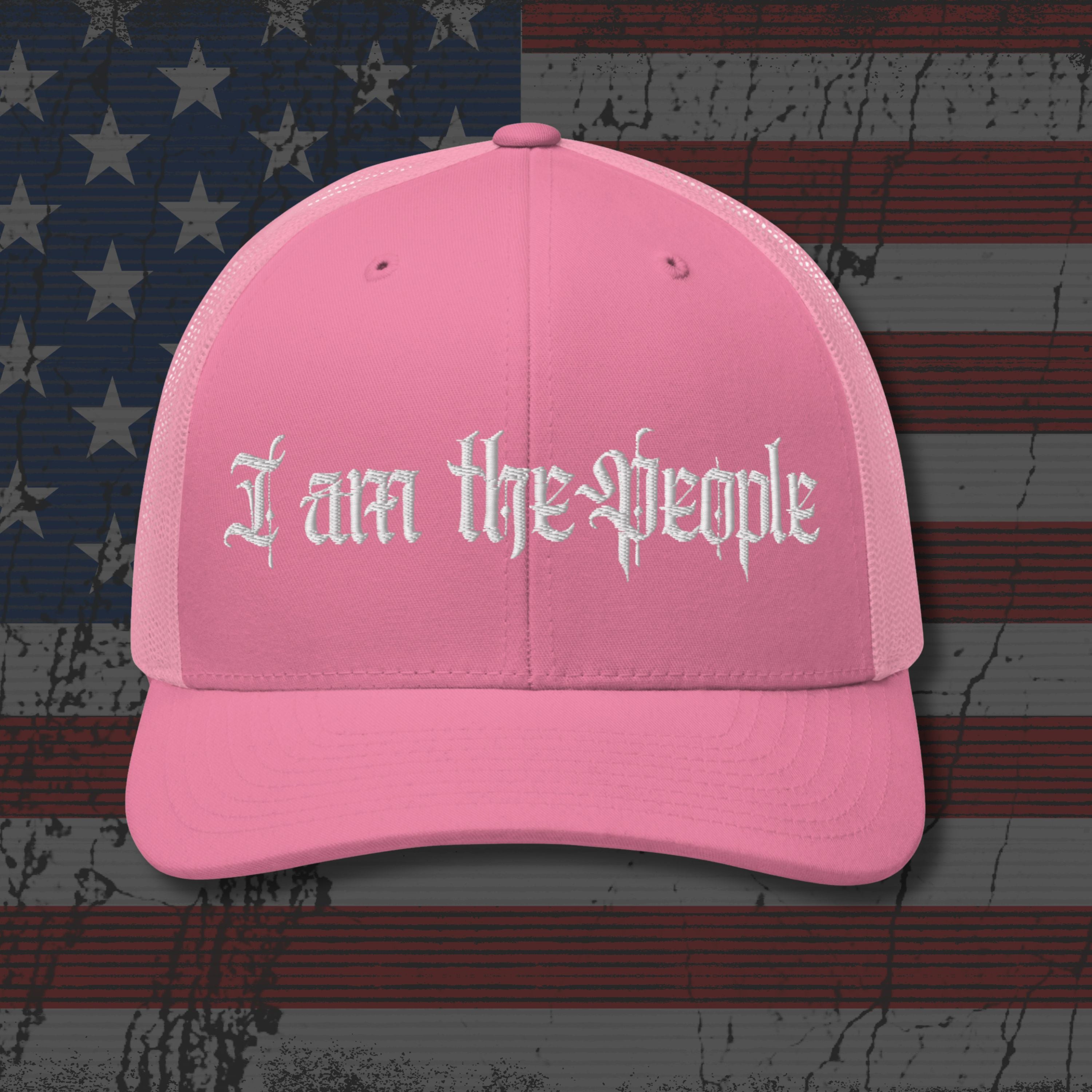 Pink cap with 'I am the people' text on an American flag background