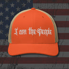 Orange cap with 'I am the People' text on an American flag background