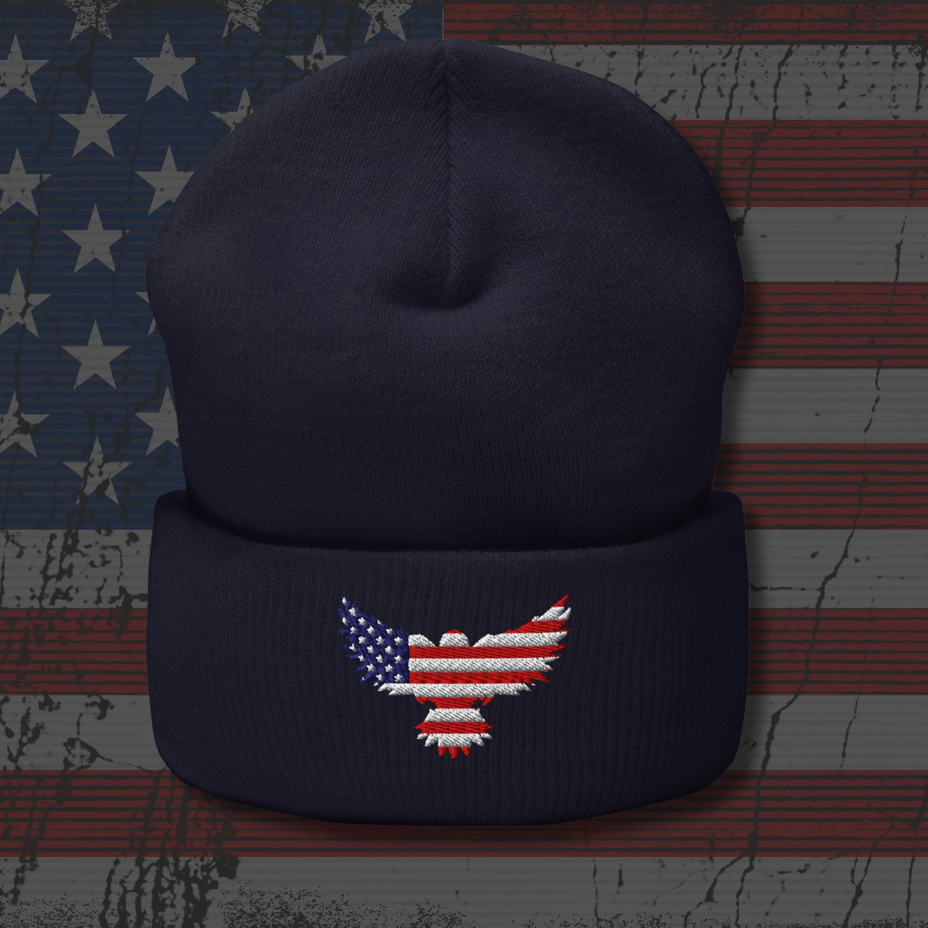 Navy blue beanie with an embroidered American flag eagle design on a textured American flag background.