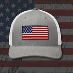 Gray and white cap with American flag patch on a distressed American flag background