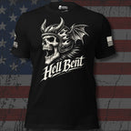 A black short-sleeve graphic T-shirt displayed against a distressed American flag background. The shirt features a large white skull wearing a horned Viking helmet with a dragon wing, above the stylized text 'Hell Bent'.