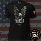 Bronze bald eagle with plaque stating "INFIDEL" across the chest of a black tee with a USA flag on the left sleeve and brand logo "INFIDEL COLLECTIVE" on the right sleeve, against a distressed USA Flag background and a badge stating "MADE IN THE USA".