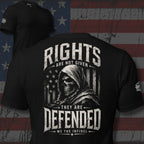 Black t-shirt with a graphic design featuring a skull and text, displayed against an American flag background.