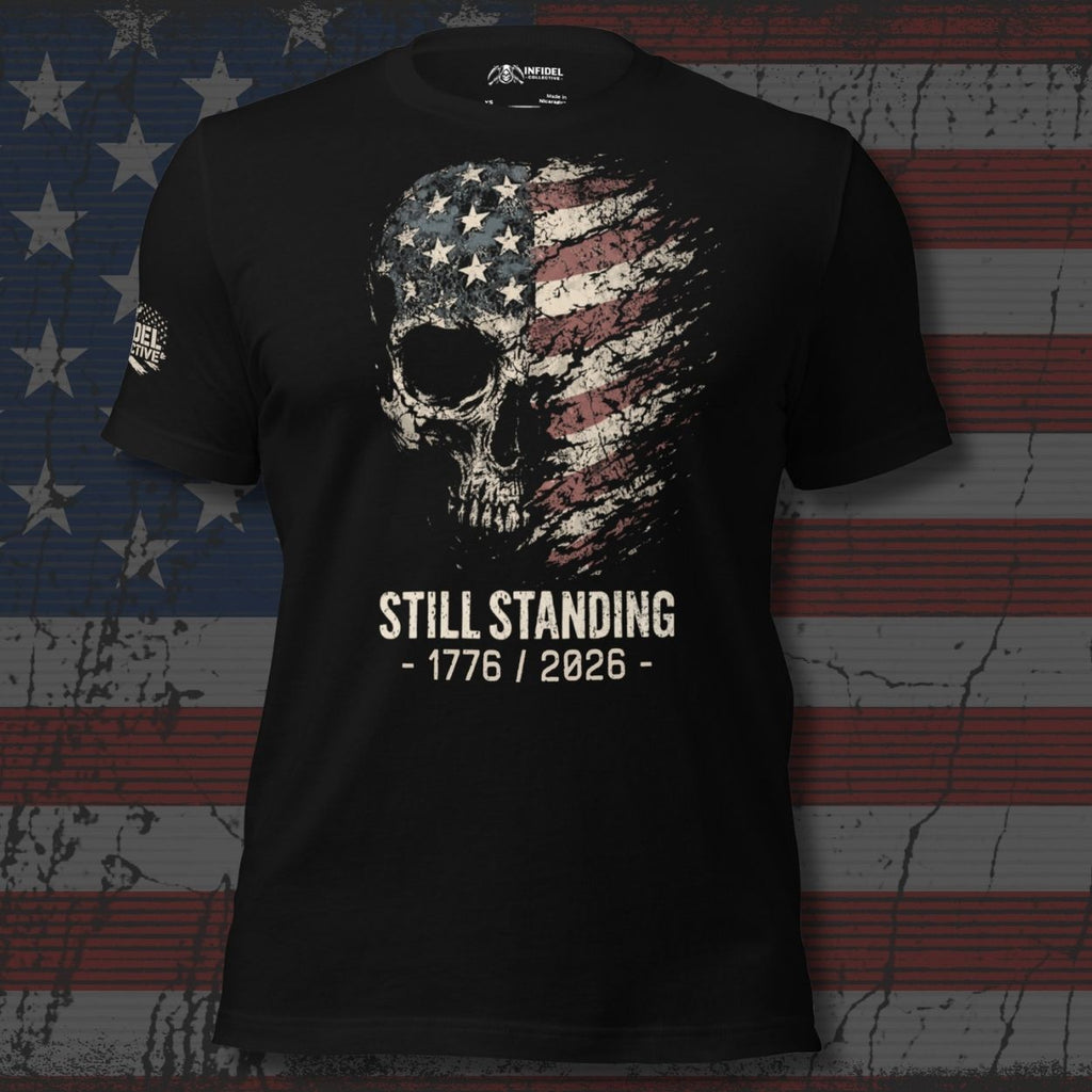Black t-shirt with skull and American flag design with text 'STILL STANDING 1776 / 2026' on a distressed American flag background