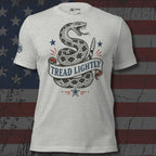 Athletic heather tee with front print of a coiled rattlesnake, patriotic stars, and a banner reading Tread Lightly