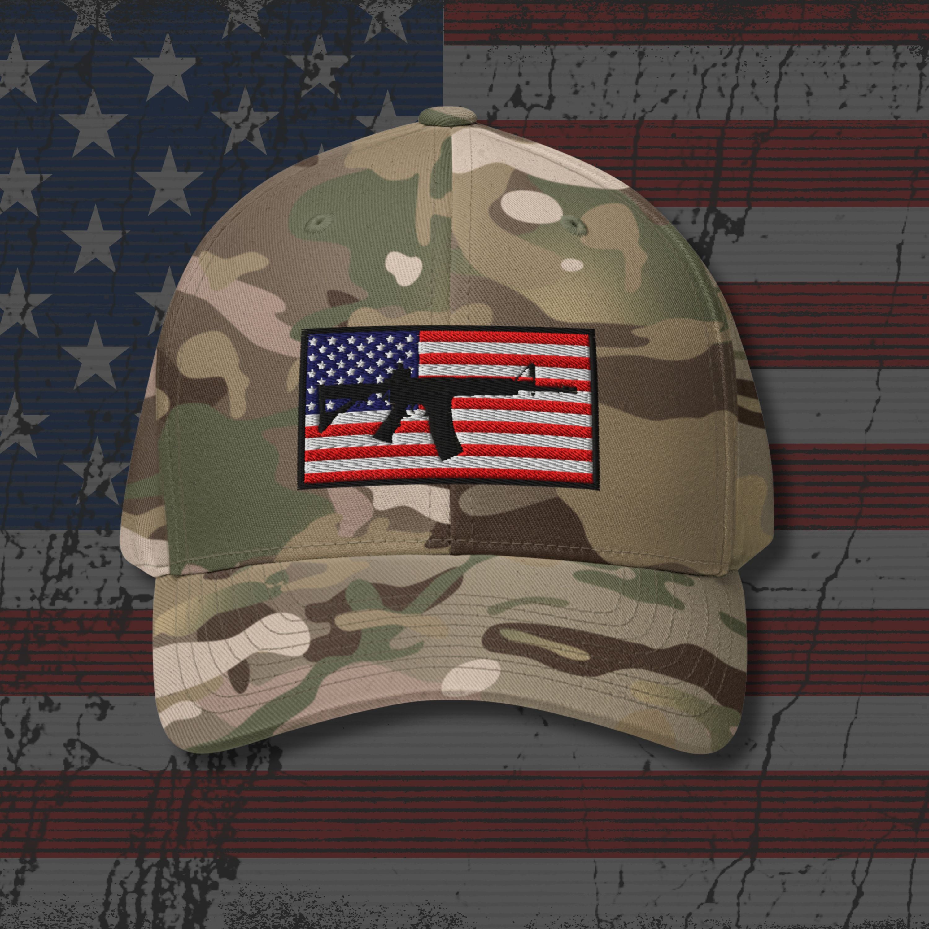 Camouflage baseball cap with an American flag patch featuring a rifle on a textured American flag background.