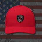 Red cap with a black and white emblem on an American flag background