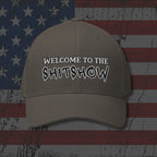 Beige cap with 'WELCOME TO THE SHITSHOW' text on an American flag background