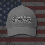 Gray cap with 'WELCOME TO THE SHITSHOW' text on an American flag background