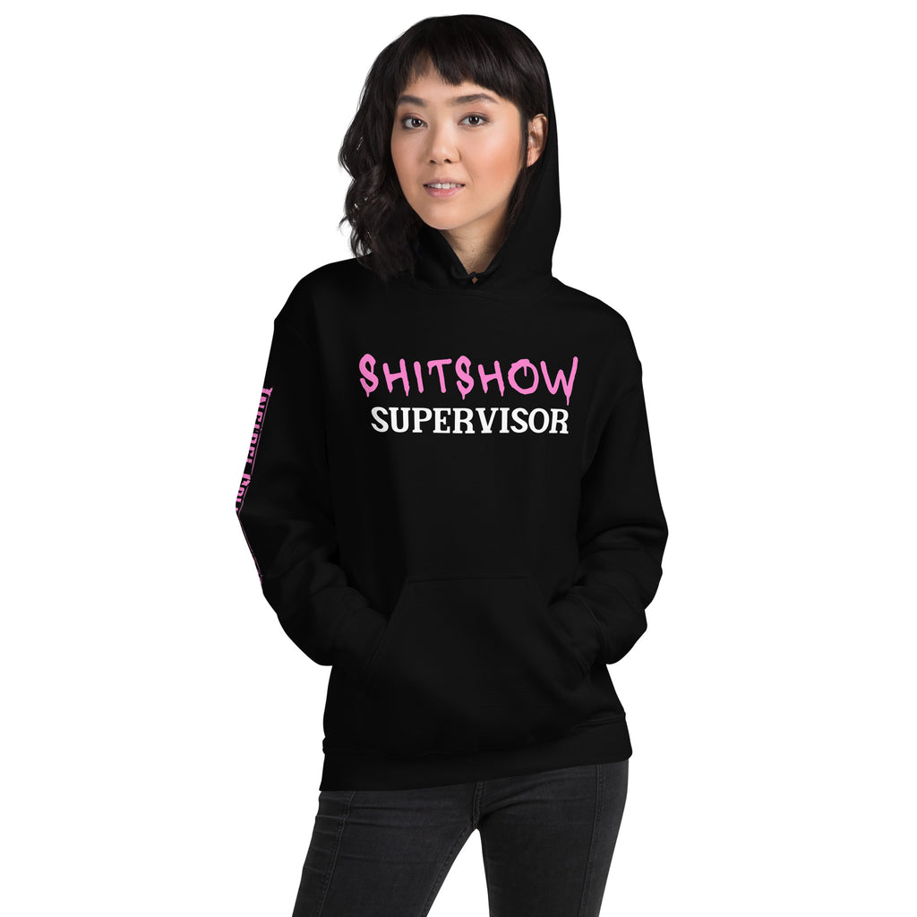 Woman wearing a black hoodie with pink and white SHITSHOW SUPERVISOR text on a white background from Infidel Collective