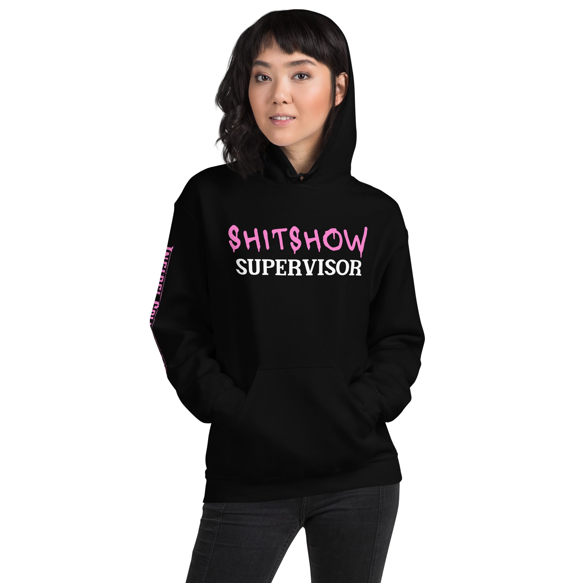 Woman wearing a black hoodie with pink and white SHITSHOW SUPERVISOR text on a white background from Infidel Collective
