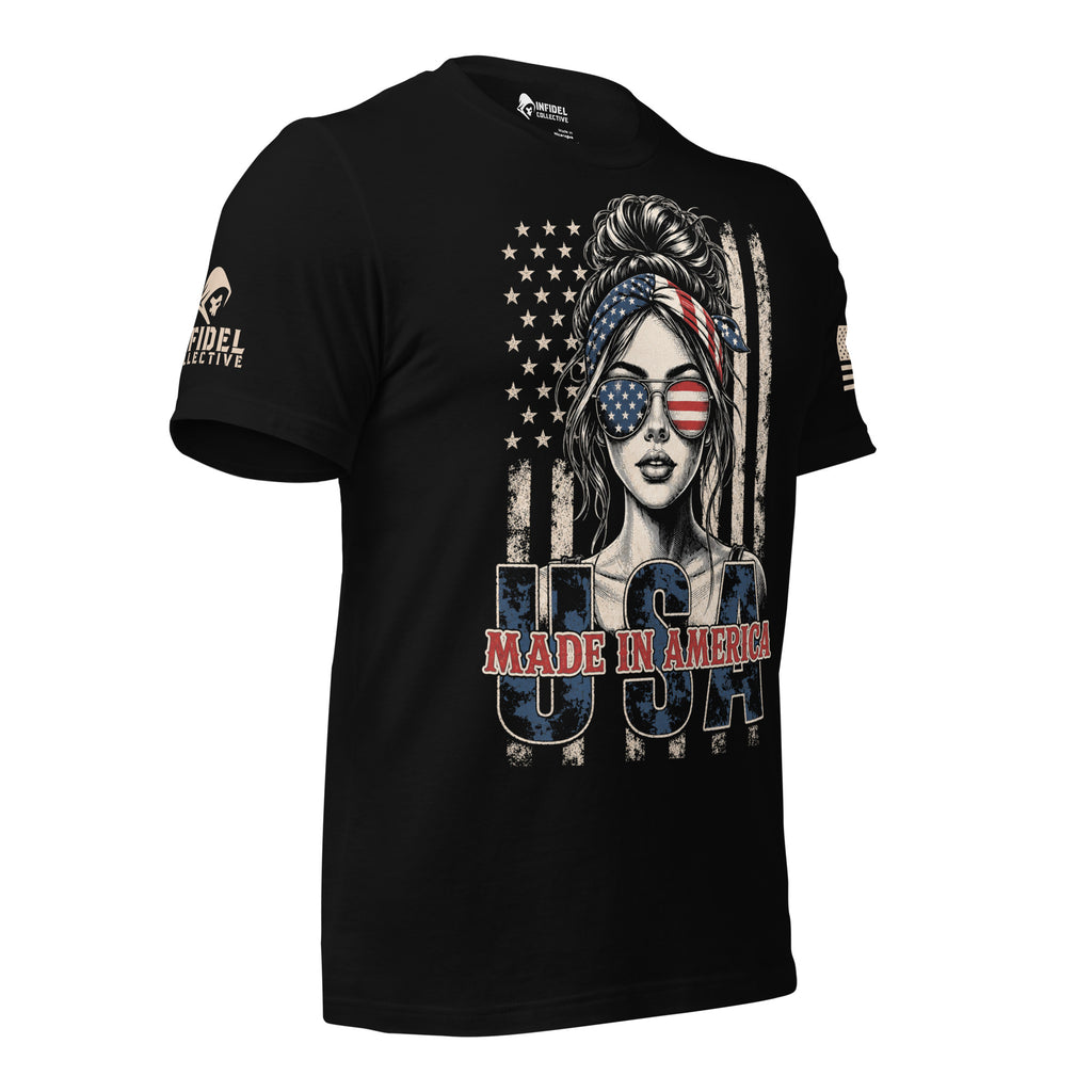 A black short-sleeve graphic t-shirt featuring a stylized woman with an American flag headband and sunglasses, set against a distressed American flag background with 'USA MADE IN AMERICA' text. The brand 'INFIDEL COLLECTIVE' is visible on the right sleeve.
