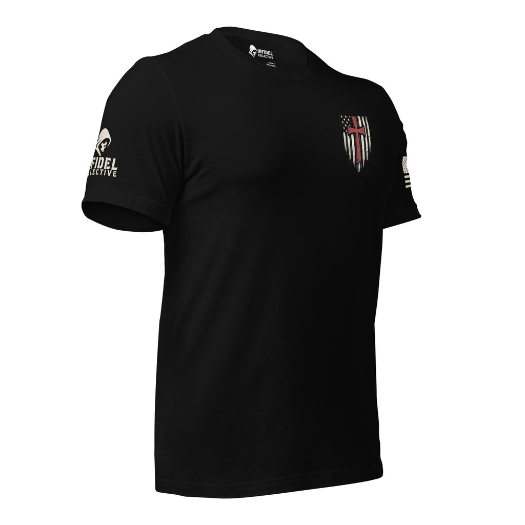 Front right view of black tee with small American flag shield and crimson red cross on the left chest. The left sleeve has an American (USA) flag and the right sleeve brand logo for INFIDEL COLLECTIVE.